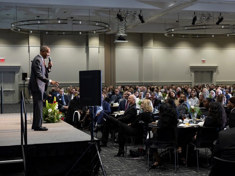 A person speaking to group at an awards ceremony.